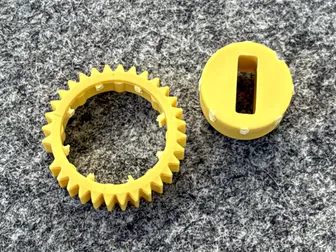 Der gebrochene gelbe Adapter des Nuki Smart Lock Ultra: links der äußere Zahnkranz, rechts das innere Stück mit dem Schlitz für den Zylinder